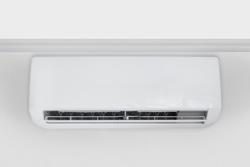 Front view on White air conditioner hanging from the ceiling on the bright wall, copy space.
