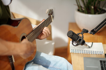 Musician using professional microphone when recording himself playing guitar