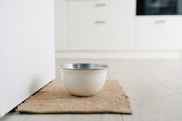 White metalic bowl with dog food or water on the floot in the kitchen home