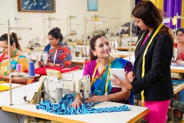 Young designer using smartphone or tablet while advice to working women group.