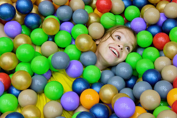 Fototapeta na wymiar The girl child is having fun playing with colored balls