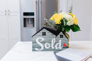 House Sold! Sign on bright kitchen counter with yellow flowers