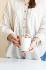girl holds a big white cup with macaroons in her hands