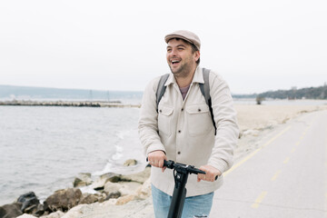 Obraz premium man in casual clothes moving on a scooter along the embankment