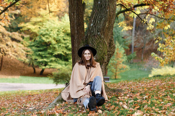 brown-haired woman in a black hat and poncho in the park