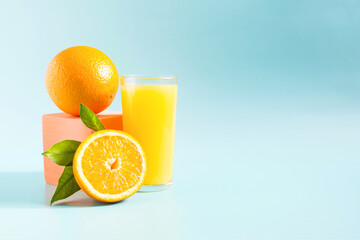 Natural orange juice with a decor of oranges and green leaves on a light background natural light.