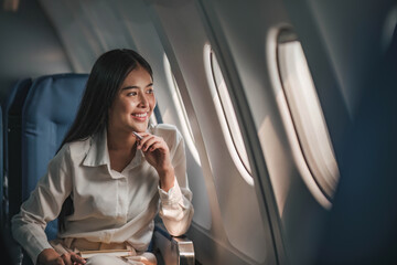 Young, beautiful girl the passenger seat in a charter plane or business jet near the porthole and smiles
