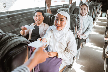 Bus passengers wearing head scarf give tickets to the bus driver