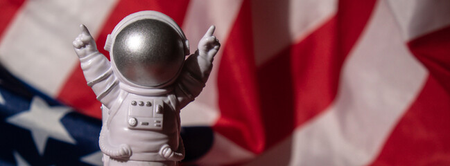 Plastic toy figure astronaut on American flag background Copy space. 50th Anniversary of USA...