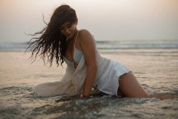 Sensuous, enticing woman with luscious curls in soaking wet dress, swimsuit pose amidst clear turquoise water of resort