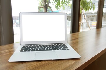 Laptop with blank screen on wooden table in front of coffeeshop cafe - technology concept