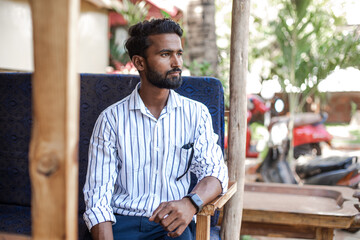 Handsome mature dark skin businessman with black hair in striped shirt on tropical vacation....