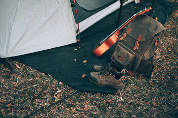 Camping equipment, bags, shoes, ukulele, tripod beside the tent in the morning. Object camp, Travel and vocation concept.
