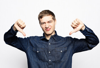 Young man wearing casual jeans shirt looking unhappy and angry showing rejection and negative with...