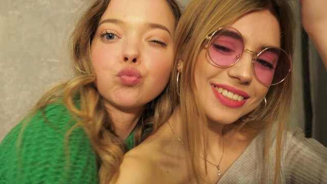 Two beautiful smiling girls in round sunglasses.Women in summer hipster clothes taking selfie pictures on  camera. Models making funny faces and having fun, Slow motion