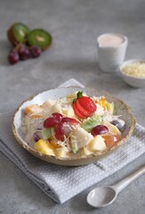Fruit salad in j rustic bowl with gray background