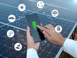 Renewable energy, Electricity, Sustainability concept. Woman hold a fully charged phone in hand on a solar panel background.