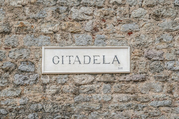 Budva, Montenegro - June 17, 2021: Signboard with the text Citadela on a stone wall in the Old Town of Budva. Sign-pointer on the facade of a historic building of the Budva Citadel