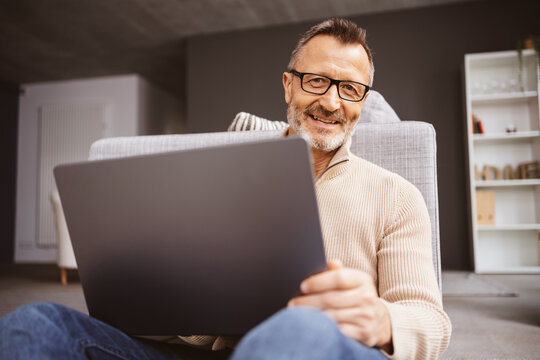 Middle-aged man working from home with a laptop and enjoying a comfortable lifestyle