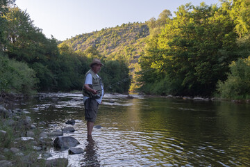Fototapeta na wymiar Senior man fishing in the river in summer
