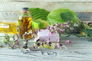 Flowers, leaves and roots of sage, soap, oils and tinctures, on a wooden background, natural ingredients, alternative medicine