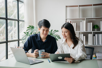 Two business workers talking on the smartphone and using laptop at the office.