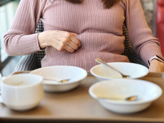 たくさんのお皿を前にしてお腹の肉をつまむ女性