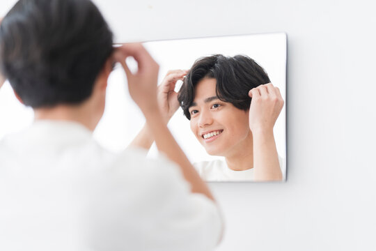 メンズビューティー/鏡を見ながらヘアセットをする若い男性