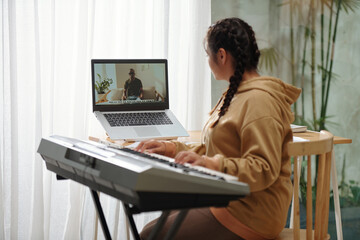 Teenage girl listening to music teacher when attending online class