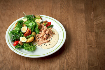 Salad with vegetables, tuna and boiled egg. Nicoise salad. Wooden background