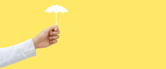 close up young man hand gesture and holding virtual umbrella icon representative of insurance on yellow background for lifestyle and protection of living concept © chinnarach