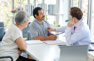 Obraz premium Asian professional successful male doctor in white lab coat with stethoscope hold medicine pill bottle showing explaining dosage and usage to elderly old senior patient and cousin in hospital office