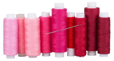 Spools with pink red purple thread and needle for sewing, supply for sewing, isolated objects 
