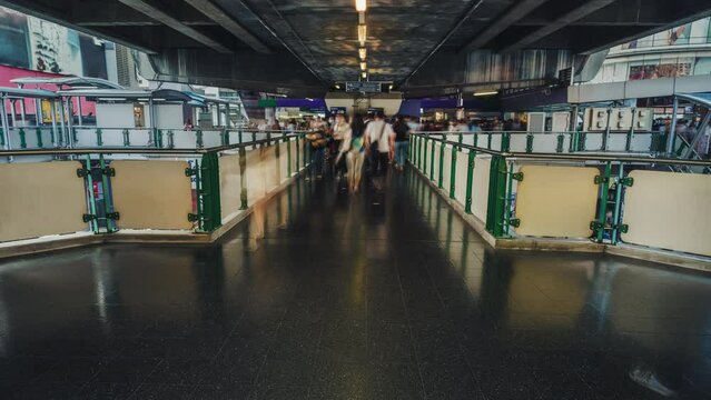Fast moving people on BTS skytrain station in Bangkok city time lapse. Motion of busy crowd of people in the evening in the skybridge. Long exposure