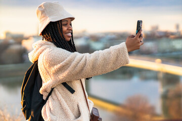 Beautiful tourist taking a picture with her phone after sites seeing all day in a new city, she's a...