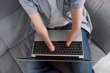 Disabled man with amputated two stump hands working typing on laptop at home sitting on sofa, hands...