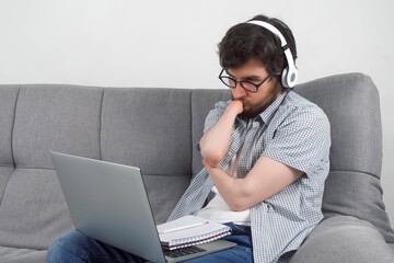 Disabled man student with amputated two stump hands studying on laptop at home and making notes in...