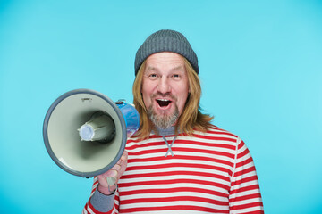 Portrait of mature man looking at camera and using speaker to announce advert standing on blue background