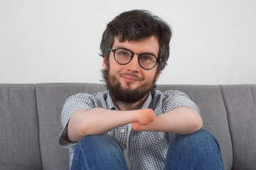 Portrait of disabled man with amputated two stump handssitting on sofa looking at camera and...