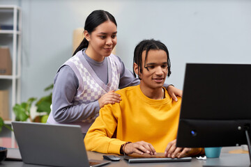 Portrait of two young people man and woman working together in IT development office and using...