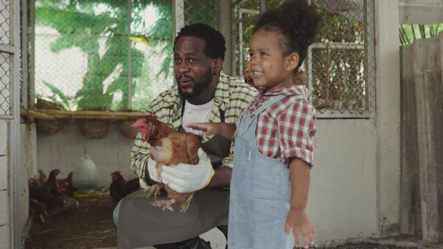 African family teaching children chicken care on sustainable farm in 4K