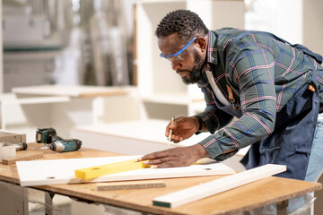 African American man does his work at furniture factory seriously and professtionally, carpenter...