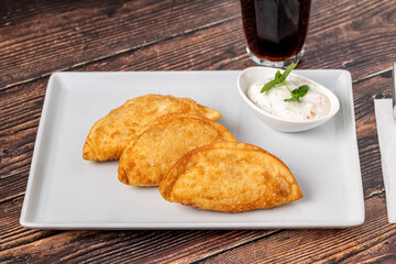 Beef Cheburek on a wooden table. Deep Fried Beef Dumplings with meat and onions. Turkish name Ci Borek or Cig Borek