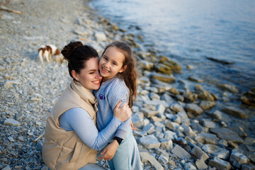 family weekend by the sea. happy mother and daughter have fun on a walk. sunset on the sea