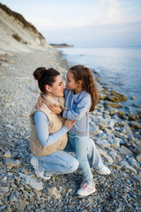 family weekend by the sea. happy mother and daughter have fun on a walk. sunset on the sea