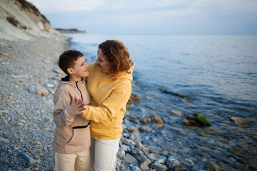 family walk on the seashore in the cold season. happy mother and son hugging each other
