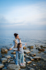 family weekend by the sea. happy mother and daughter have fun on a walk. sunset on the sea