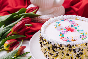 White cake decorated with cream near red tulips