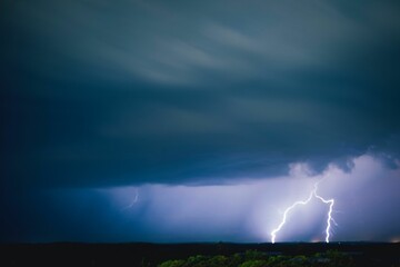 Long exposure of dramatic clouds in the sky and lightning illuminating the area