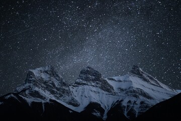 Scenic shot of the sky at night during snowy weather and rocky mountains with white peaks